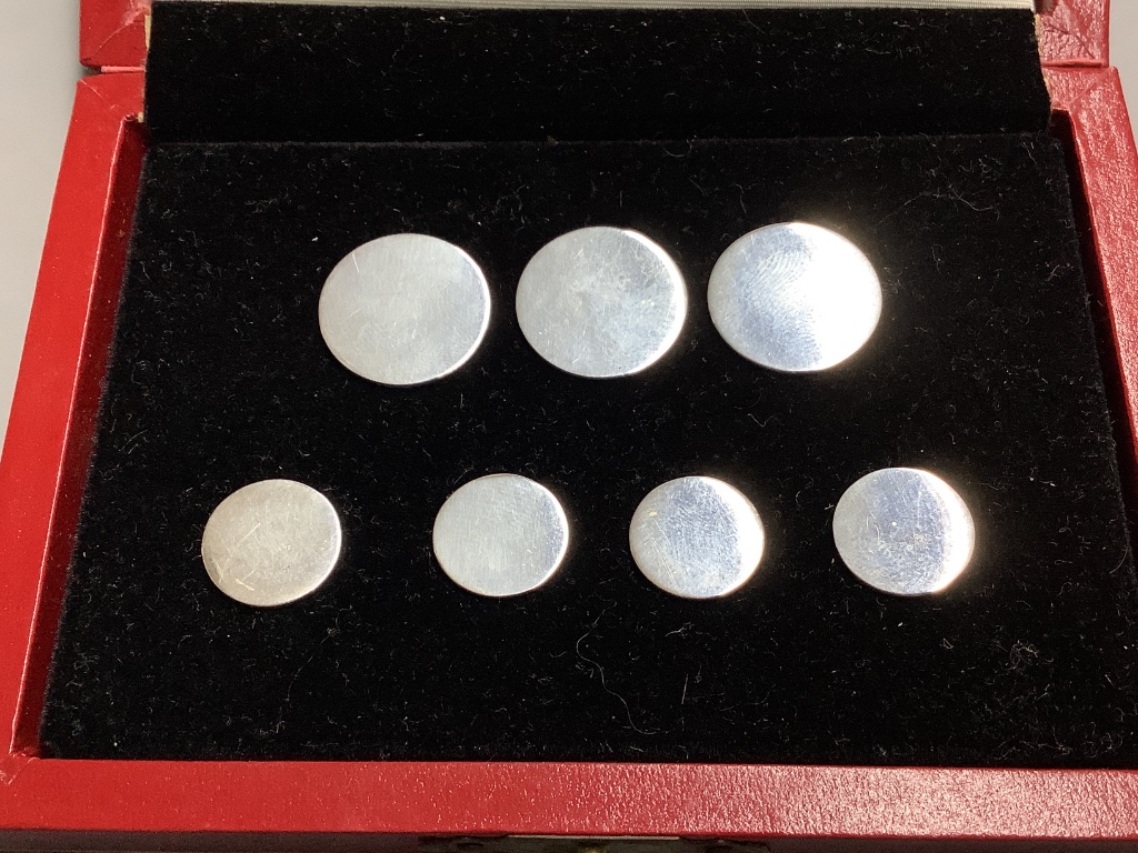 A cased set of seven sterling white metal buttons (two sizes), five bearing the stamp 'Cartier', largest diameter 19mm